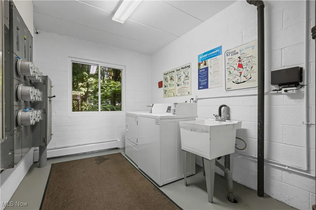 Community laundry featuring concrete block wall and washer and clothes dryer