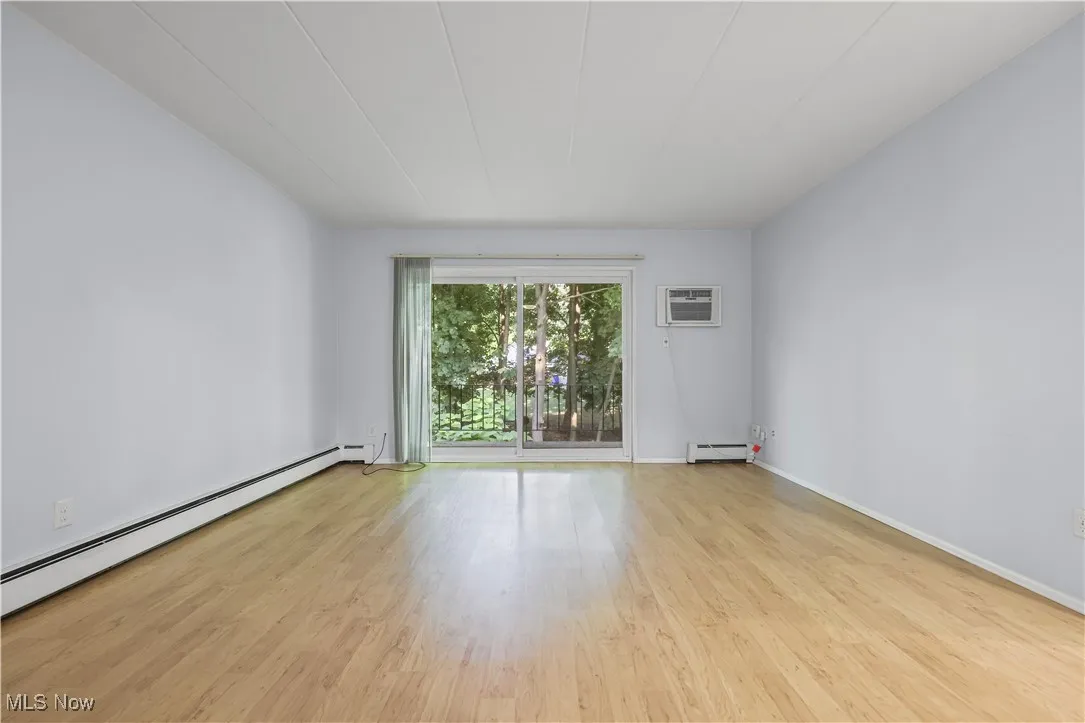 Spare room featuring laminate floors, a baseboard radiator, a wall mounted AC, and baseboard heating