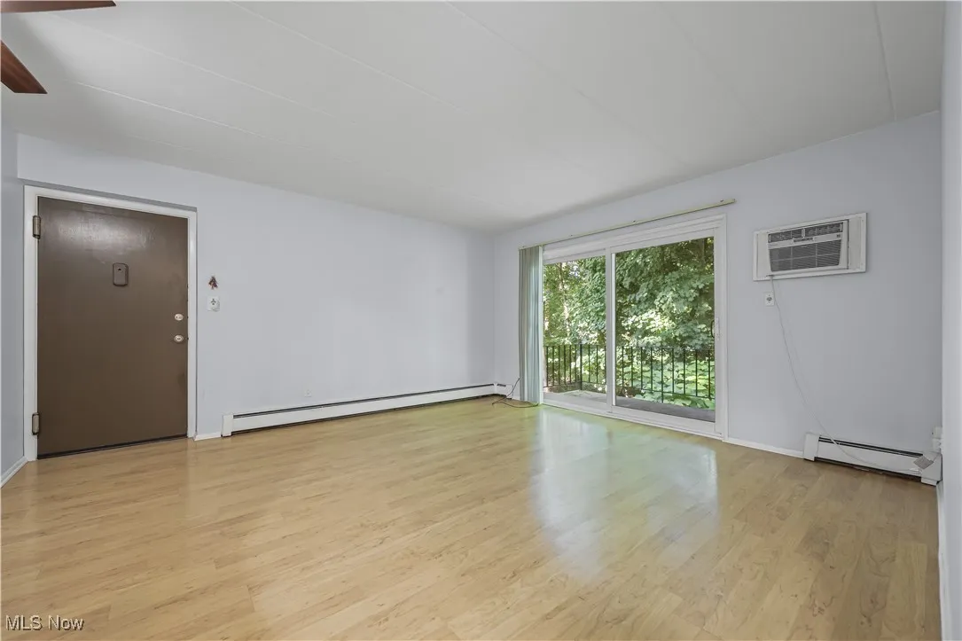 Spare room with baseboard heating, laminate flooring, and a wall mounted AC