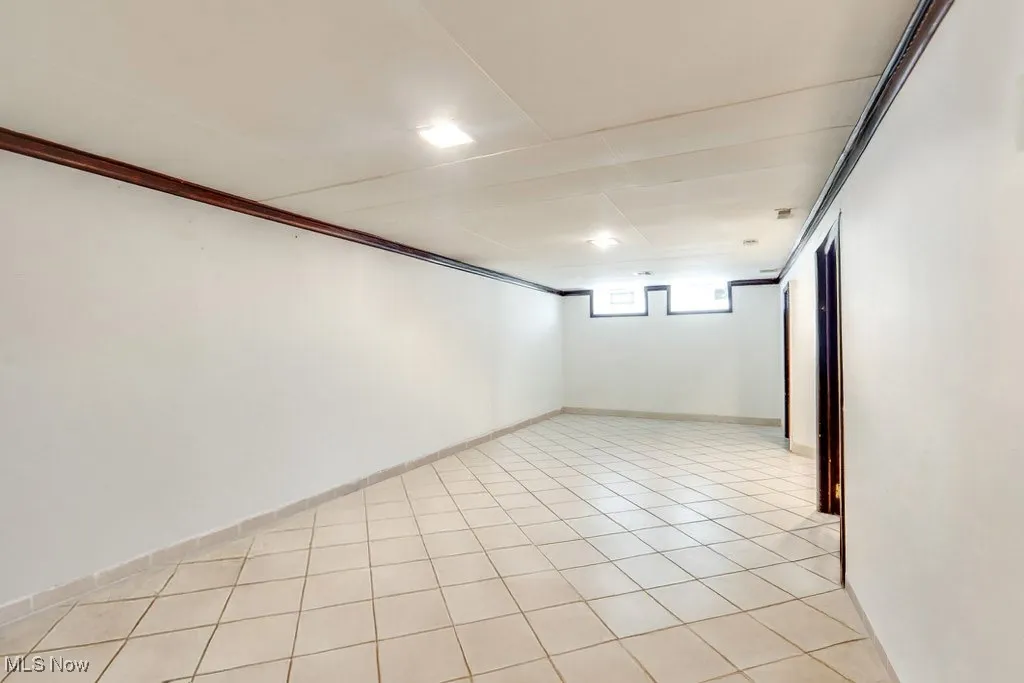 Spare room with ornamental molding and light tile patterned floors