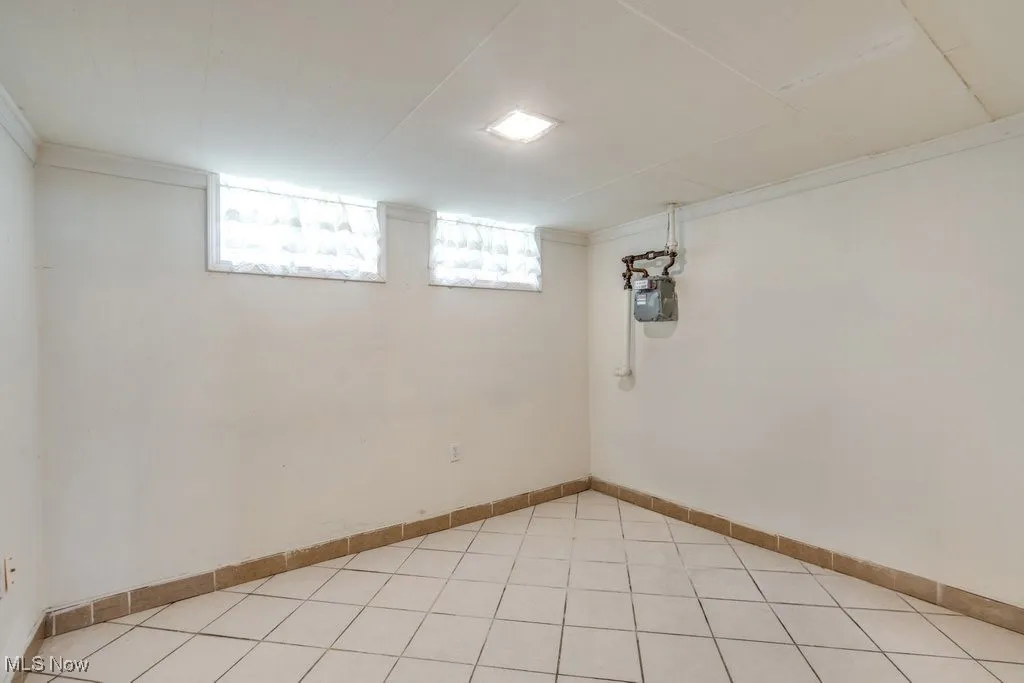 Basement featuring crown molding and light tile patterned floors