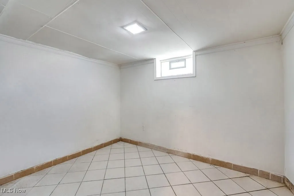 Basement with ornamental molding and light tile patterned floors