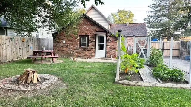 Back of house with a vegetable garden, a fire pit, and a fenced backyard