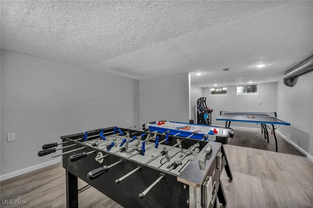 Recreation room with wood finished floors and a textured ceiling