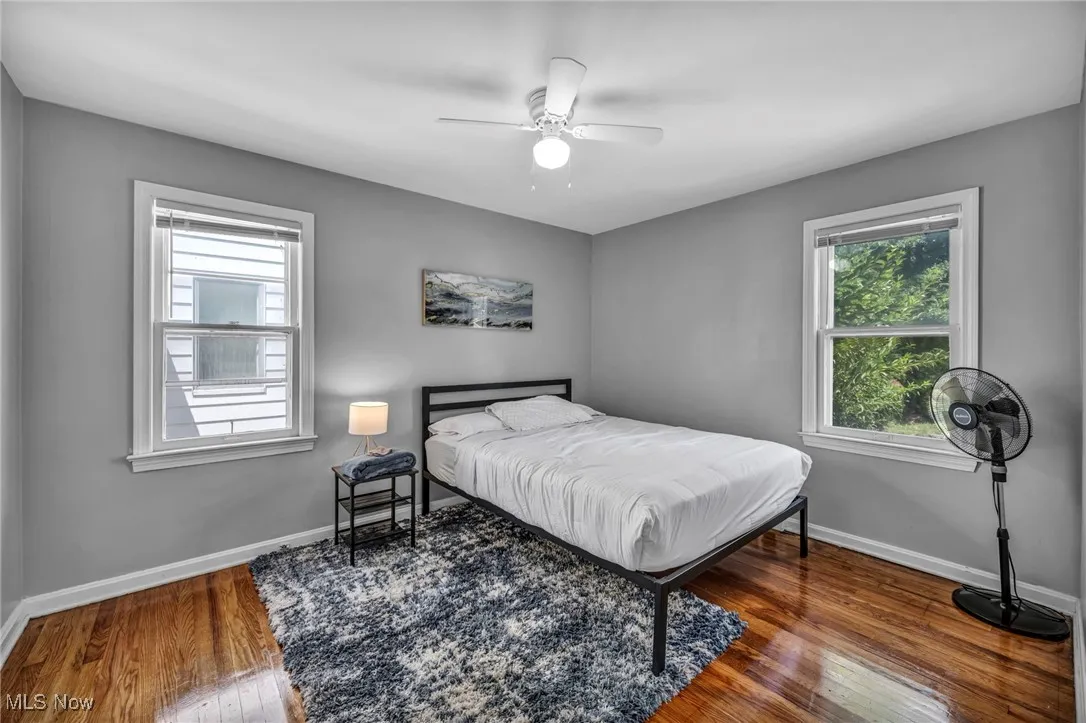 Bedroom featuring wood finished floors, multiple windows, and ceiling fan