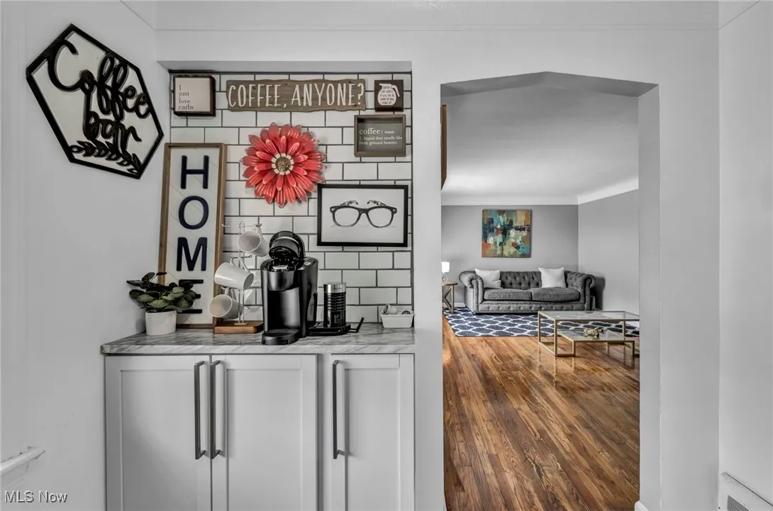 Bar area with wood finished floors, crown molding, and backsplash