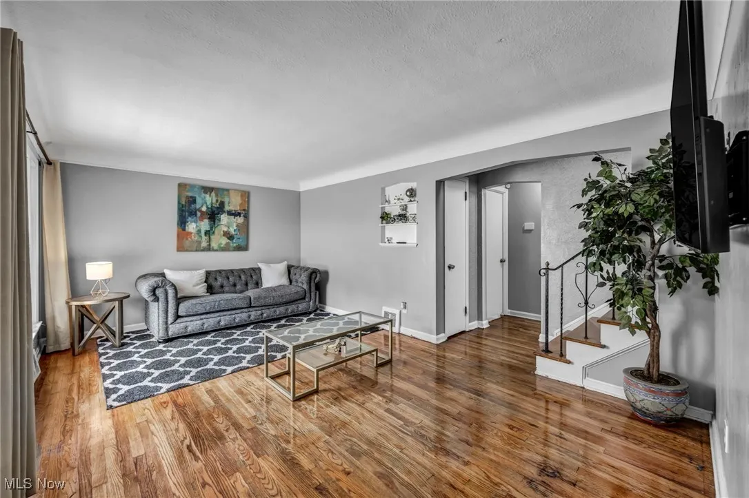 Living room with wood finished floors, a textured ceiling, stairway, and arched walkways