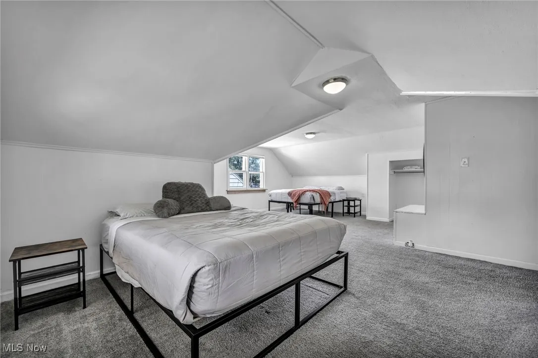 Bedroom with vaulted ceiling and carpet floors