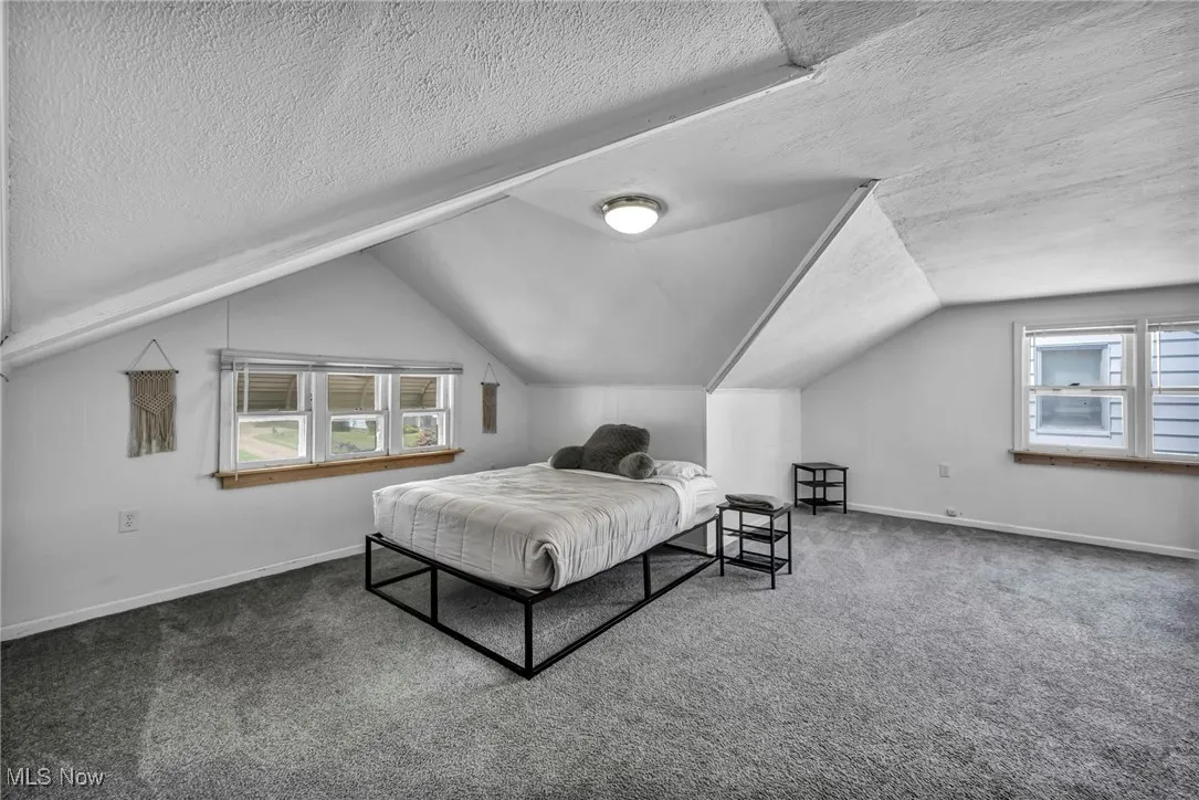 Carpeted bedroom featuring a textured ceiling and lofted ceiling