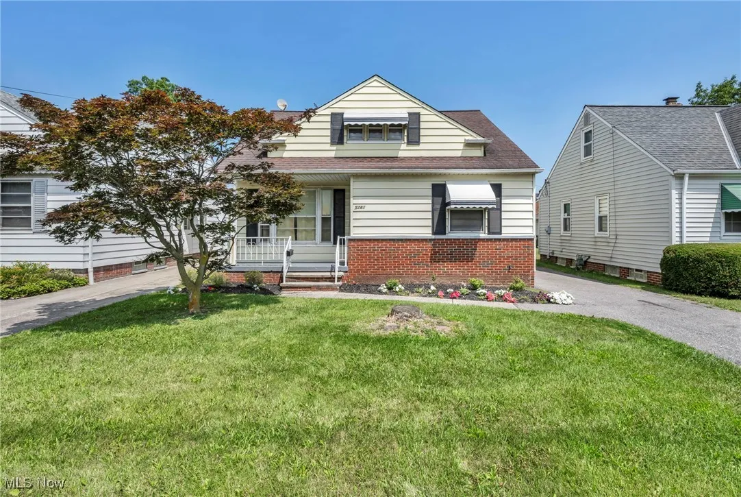 View of front of property featuring a front lawn, covered porch, a shingled roof, and brick siding