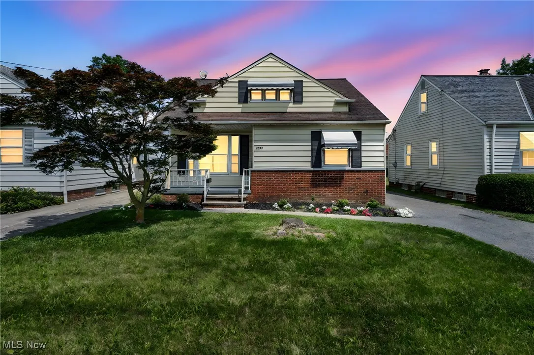 View of front of house with covered porch, a front lawn, and brick siding