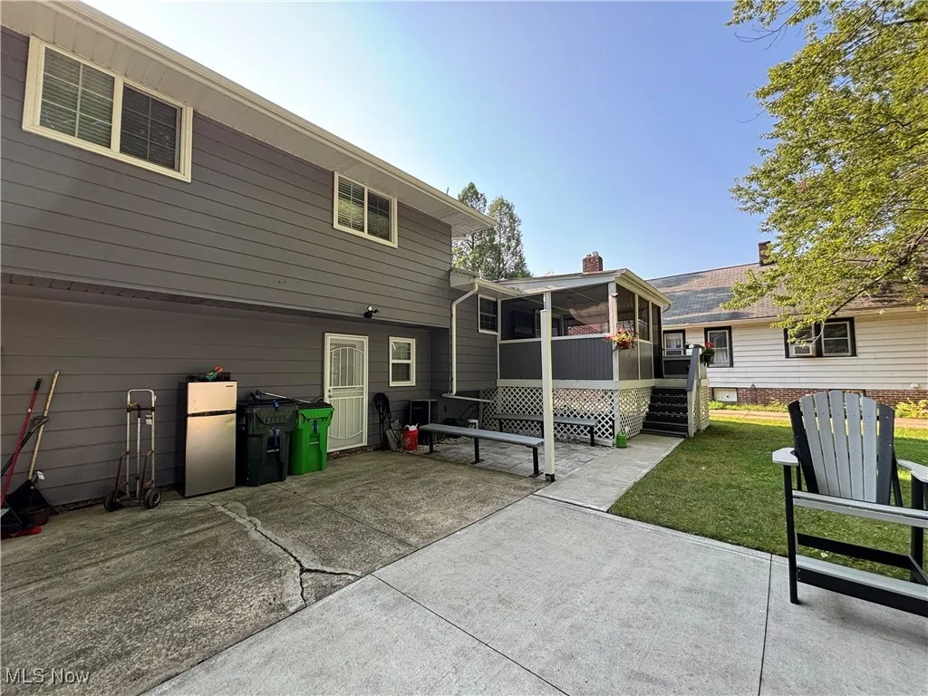Back of house featuring a sunroom, a patio, a chimney, and a yard