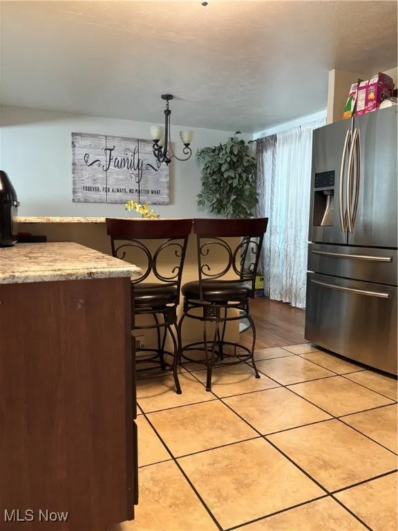 Kitchen featuring fridge, light tile patterned floors, and a chandelier