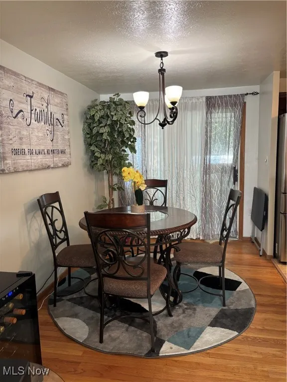 Dining area with a textured ceiling, wood finished floors, and a chandelier