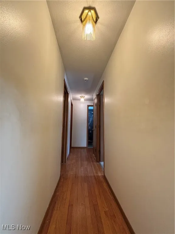 Corridor featuring a textured ceiling and wood finished floors
