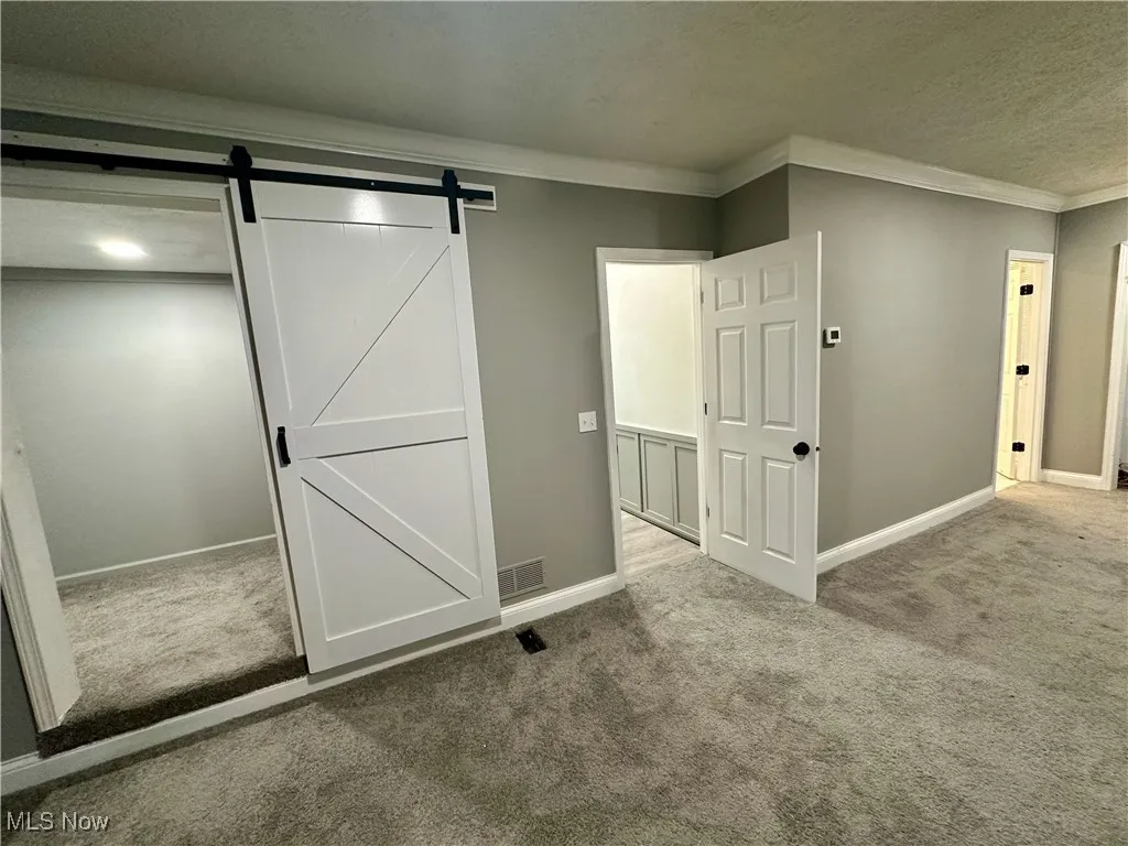 Unfurnished bedroom with carpet floors, crown molding, and a textured ceiling
