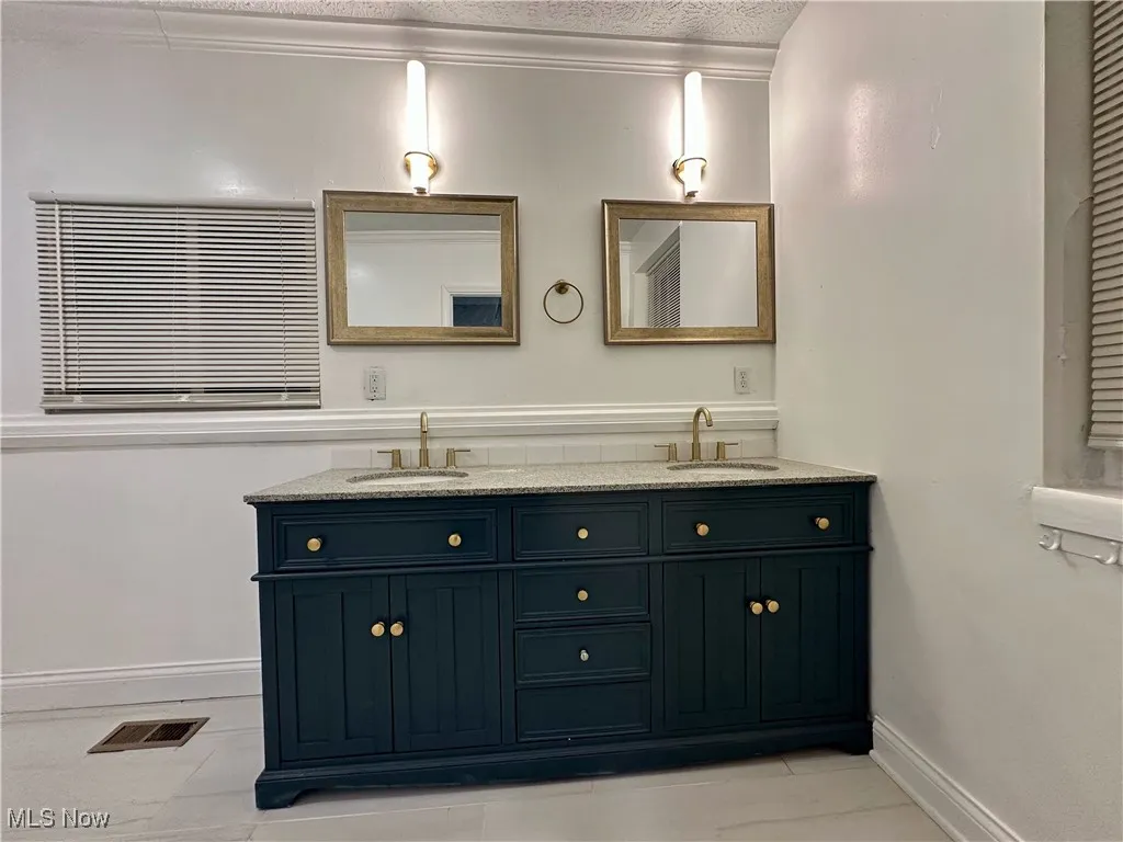 Full bathroom featuring double vanity and baseboards