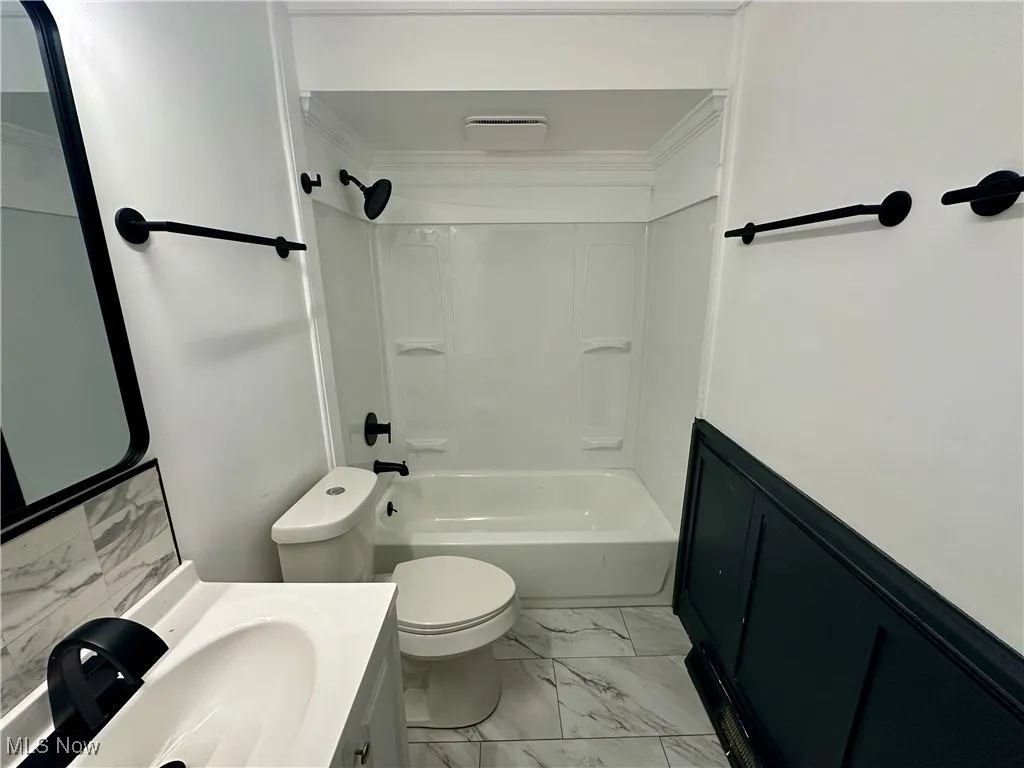 Bathroom with marble look tiles, vanity, and washtub / shower combination