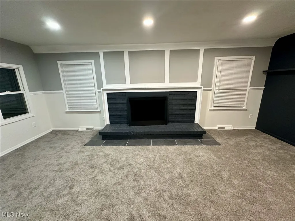 Unfurnished living room featuring a brick fireplace, carpet, recessed lighting, and crown molding