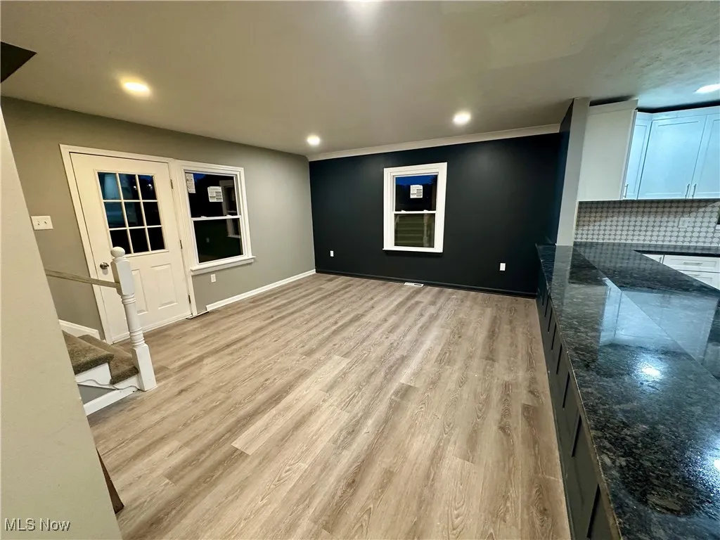 Unfurnished living room featuring recessed lighting, light wood finished floors, stairway, and ornamental molding