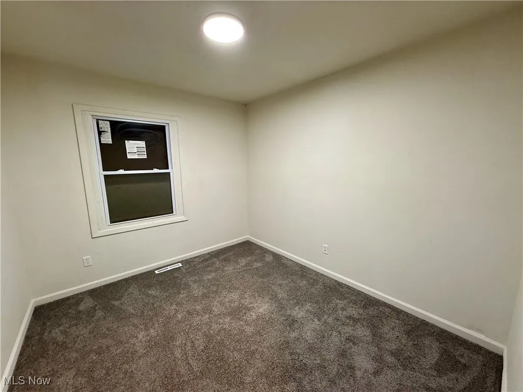 Spare room with dark colored carpet and baseboards