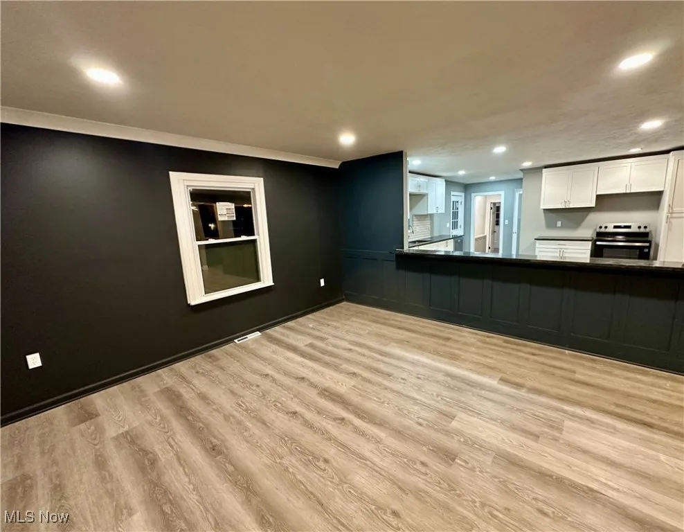 Kitchen with recessed lighting, white cabinets, stainless steel electric range, light wood finished floors, and dark countertops