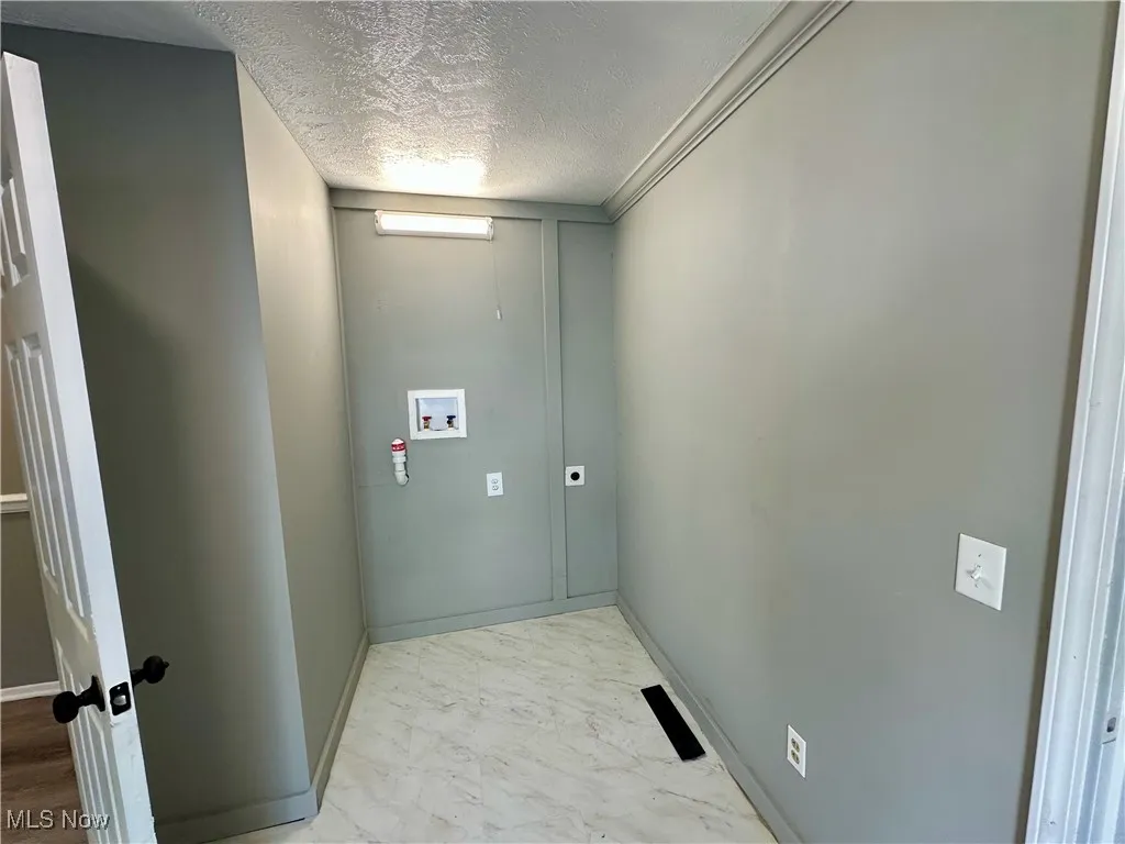 Laundry area featuring a textured ceiling, hookup for a washing machine, and hookup for an electric dryer