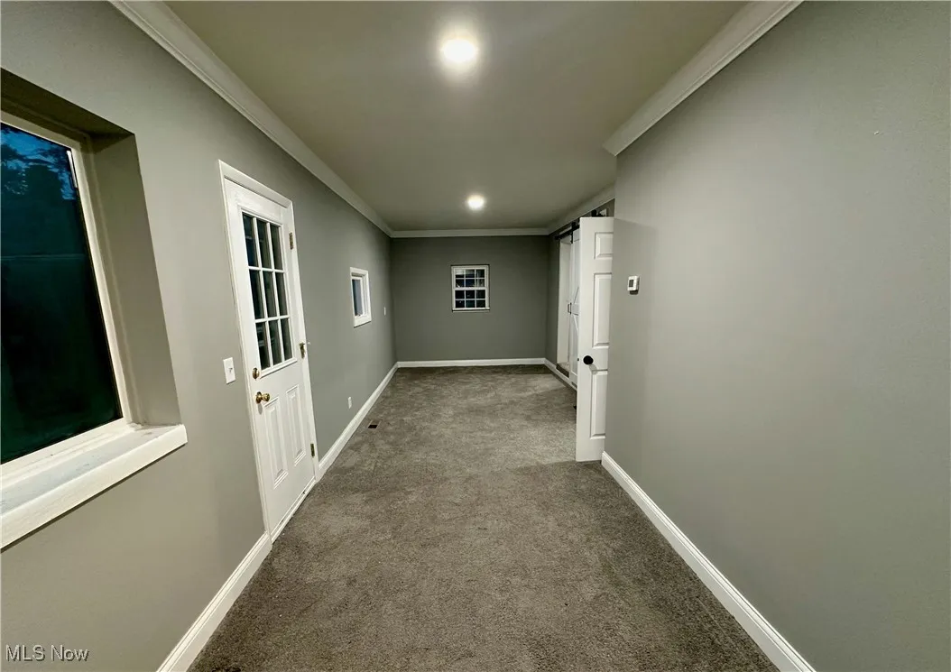 Corridor featuring carpet and crown molding