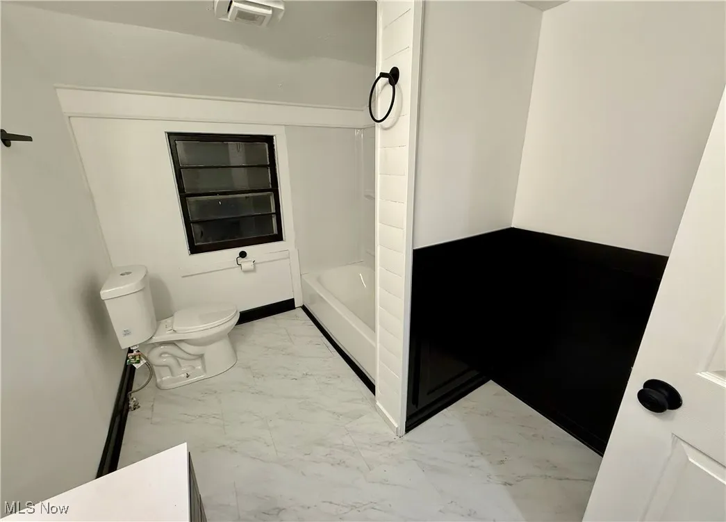 Bathroom featuring marble look tiles and toilet