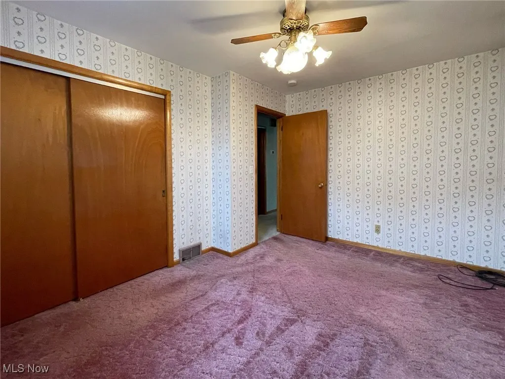 Carpeted bedroom with double closet and celing fan.