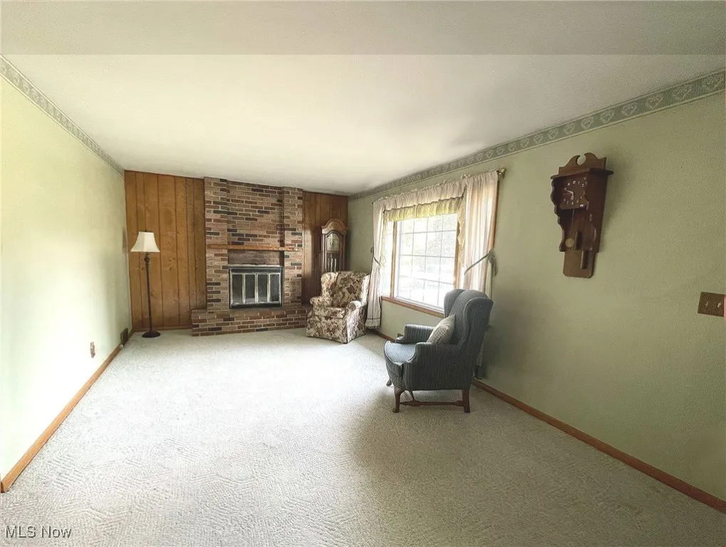 Living room with picture window and lovely fireplace with brick surround.