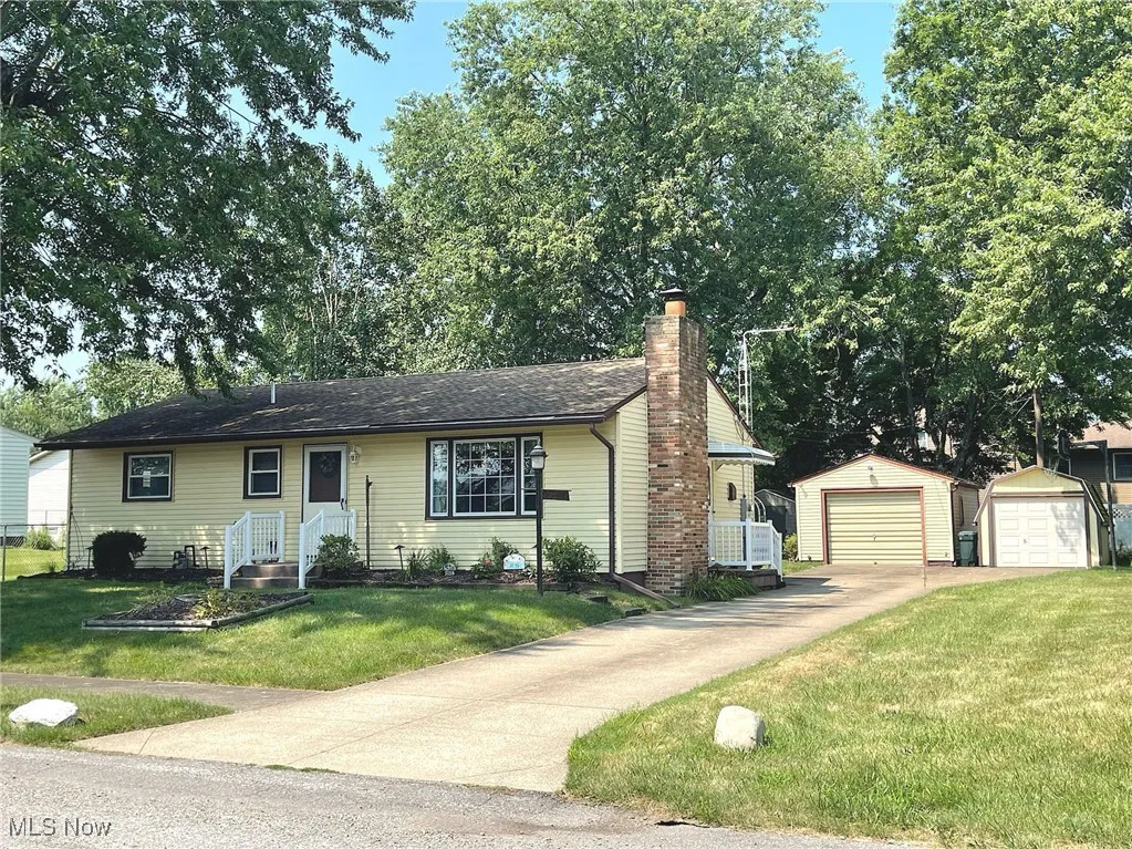 1-Sty ranch featuring a garage, an outbuilding, chimney, and a front yard