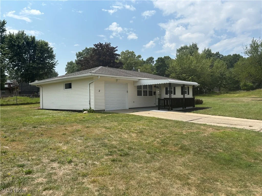 View of front of house featuring an attached garage, driveway, and a front lawn