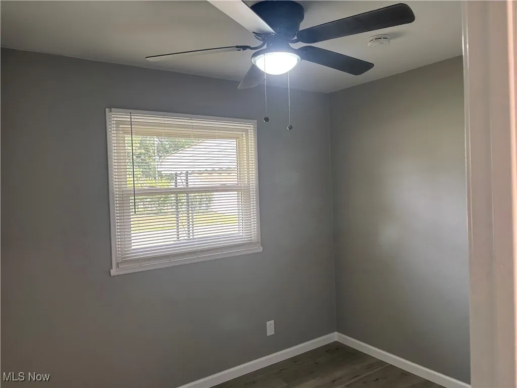 Empty room with dark wood-type flooring and ceiling fan