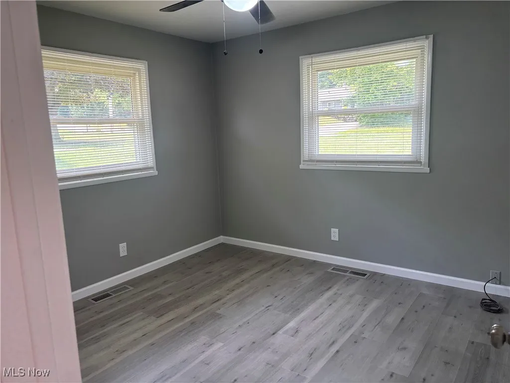 Unfurnished room featuring healthy amount of natural light and wood finished floors