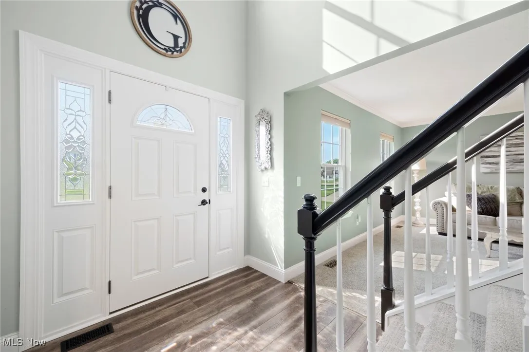 Foyer featuring healthy amount of natural light, Light LVT  floors, stairs and crown molding