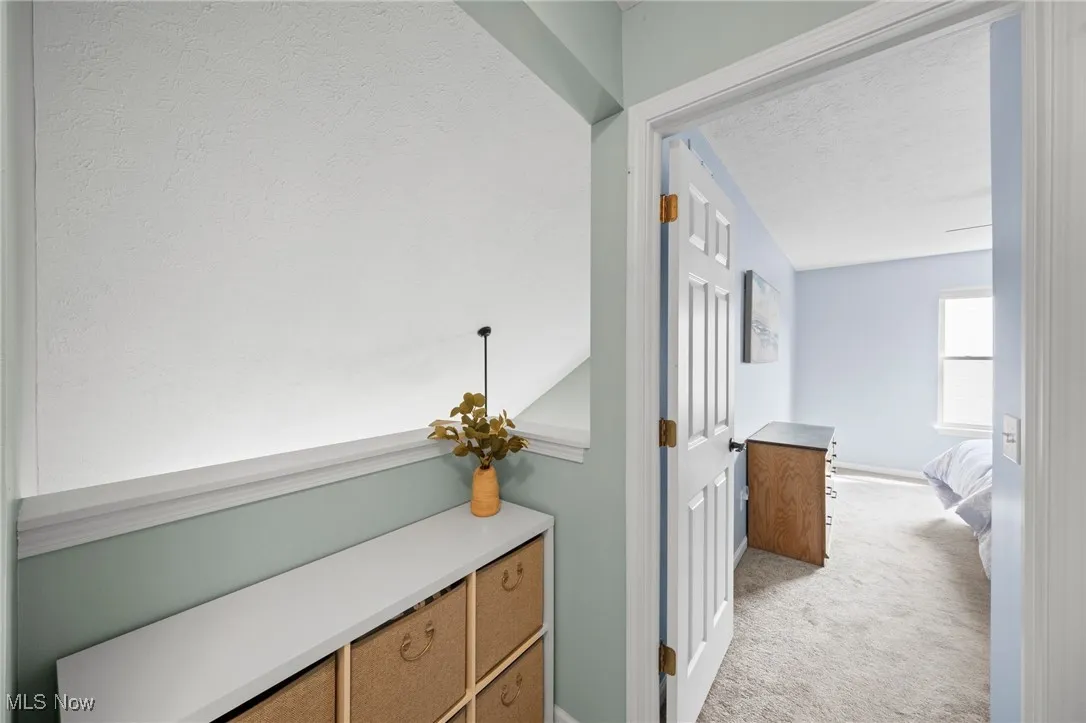 Hall with a textured ceiling and light colored carpet