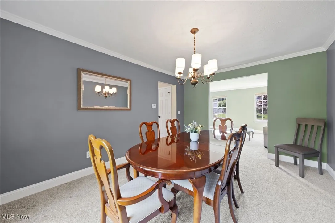 Dining room featuring light carpet, a chandelier, and crown molding
