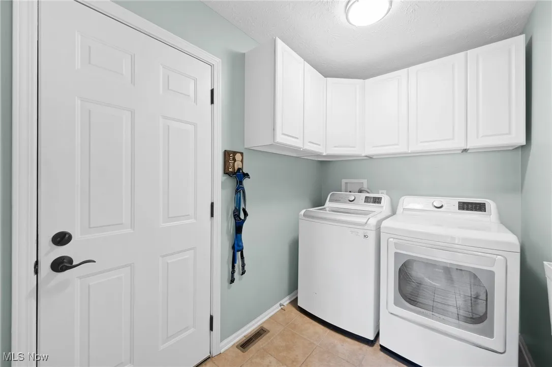 Laundry room with cabinet space, independent washer and dryer & light tile patterned floors