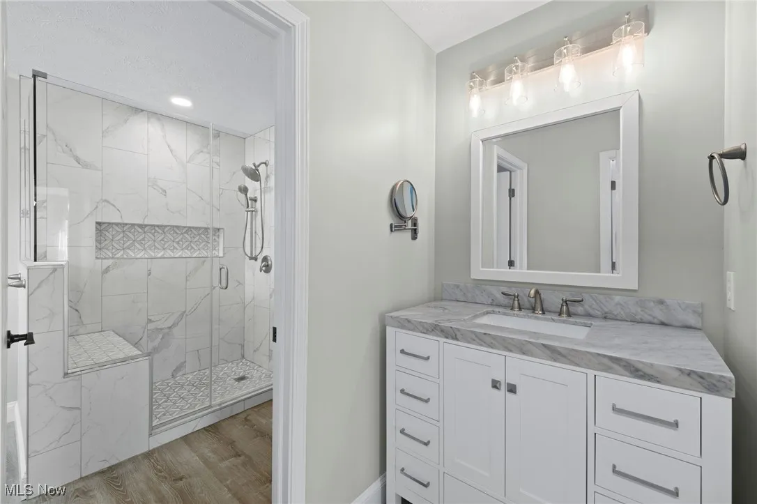 Full bathroom with a custom tile shower, LVT floors, and vanity