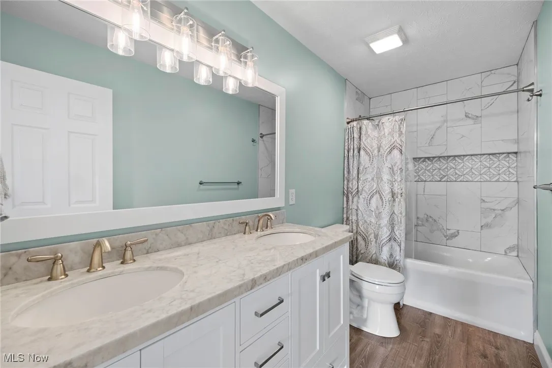 Full bath with custom tile shower / tub combo, double vanity, and LVT finished floors