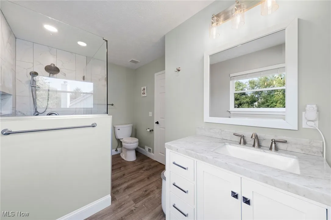 Bathroom with walk in shower, vanity, LVT floors and recessed lighting