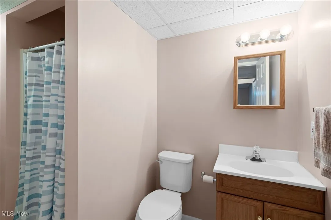 Bathroom featuring a paneled ceiling, vanity, and a shower