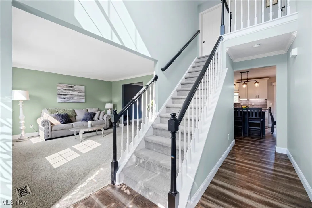 Foyer entry w stairs  -featuring crown molding, a towering ceiling, and LVT floors