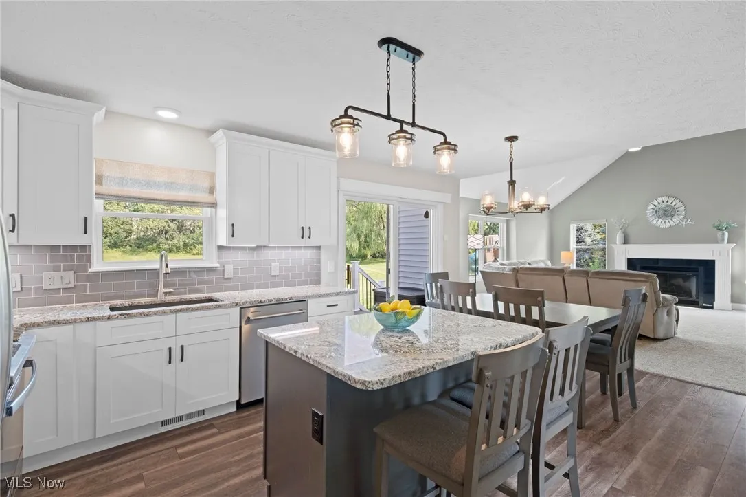 Kitchen with open floor plan, white cabinetry, island w breakfast bar and view to great room