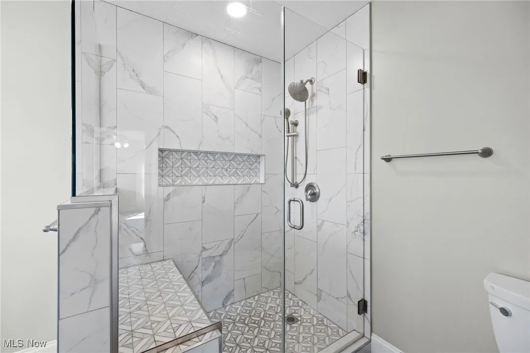 Full bath featuring a custom tile shower with seat