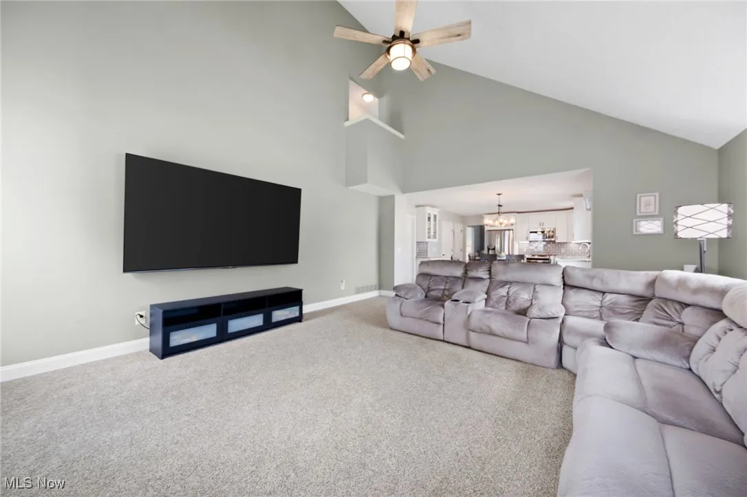 Carpeted living room featuring ceiling fan, and high vaulted ceiling - and alcove lookout from 2nd floor