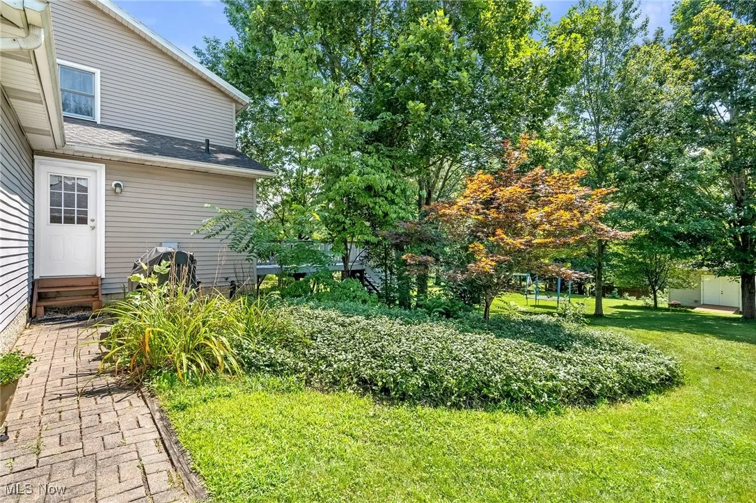 Another view of backyard with brick walkway leading to back door