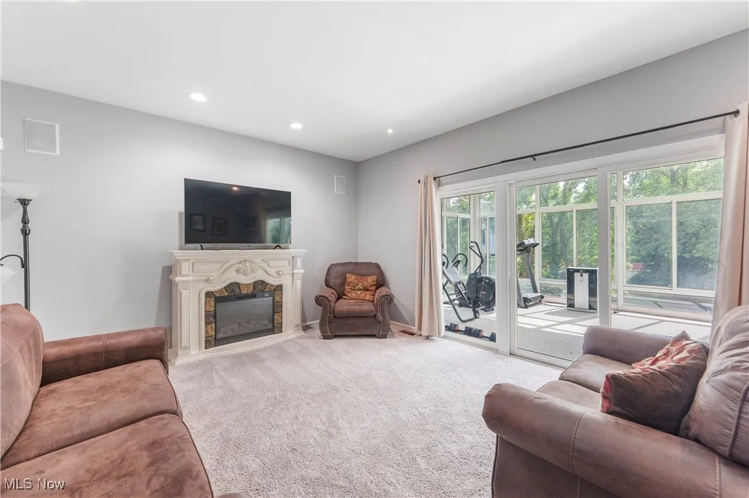 Living area featuring a glass covered fireplace, carpet floors, and recessed lighting