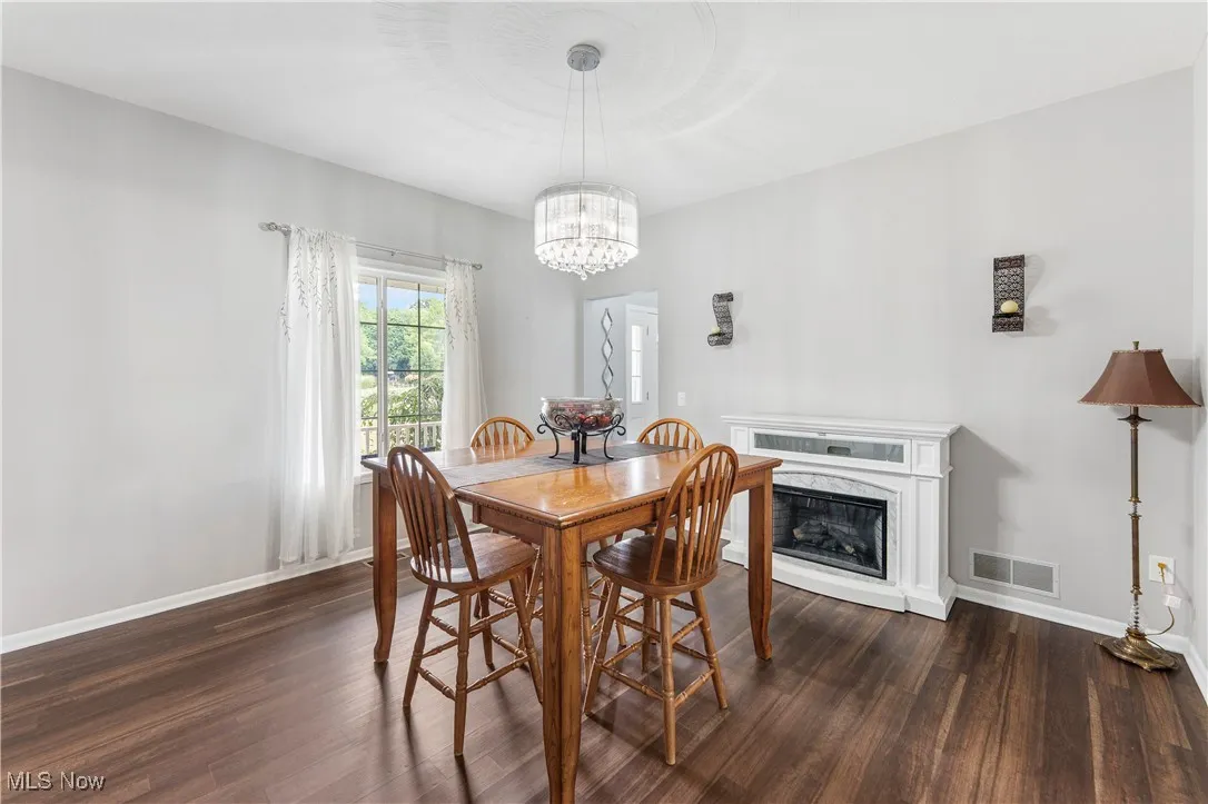 Dining space with dark wood-style flooring, a fireplace, and a chandelier